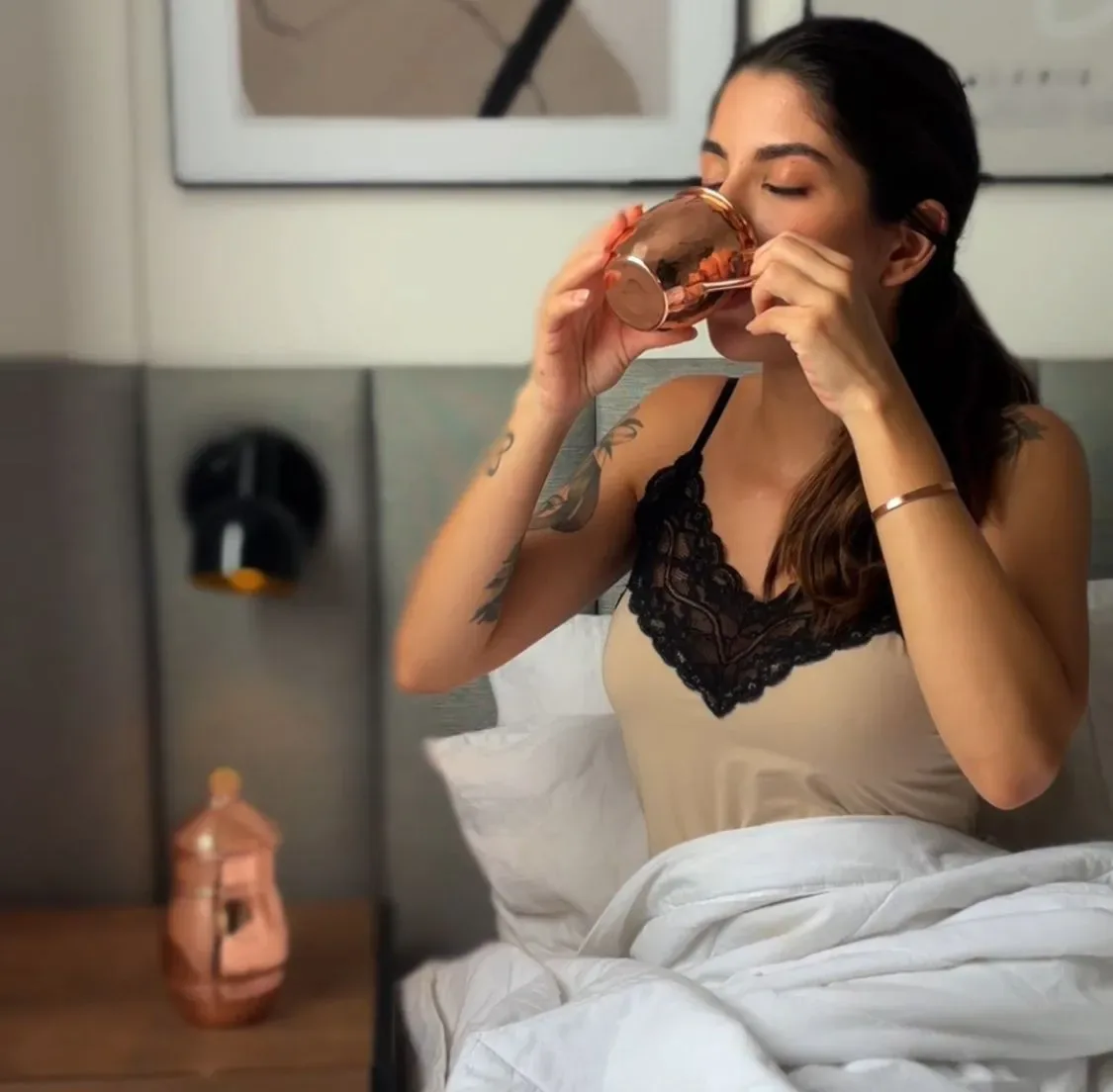 Mulher bebendo água na caneca de cobre