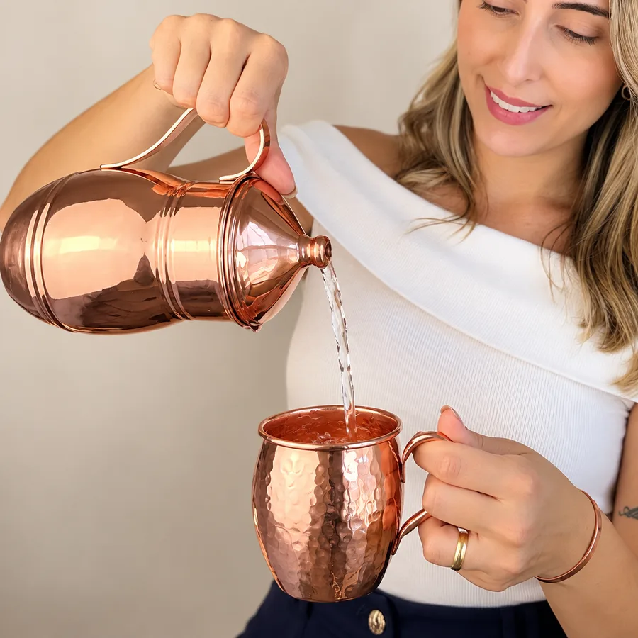Jarra de cobre servindo água na caneca de cobre